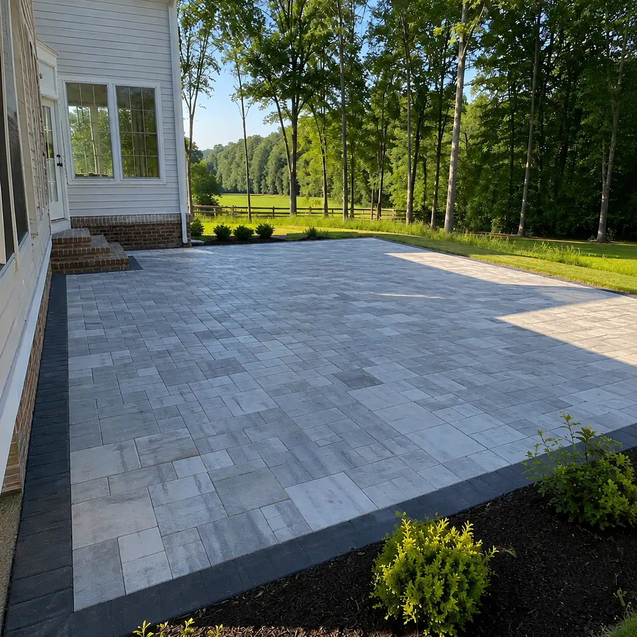 Concept rendering: gray paver patio with a dark soldier-course border beside a home and lawn in Wilmington, DE